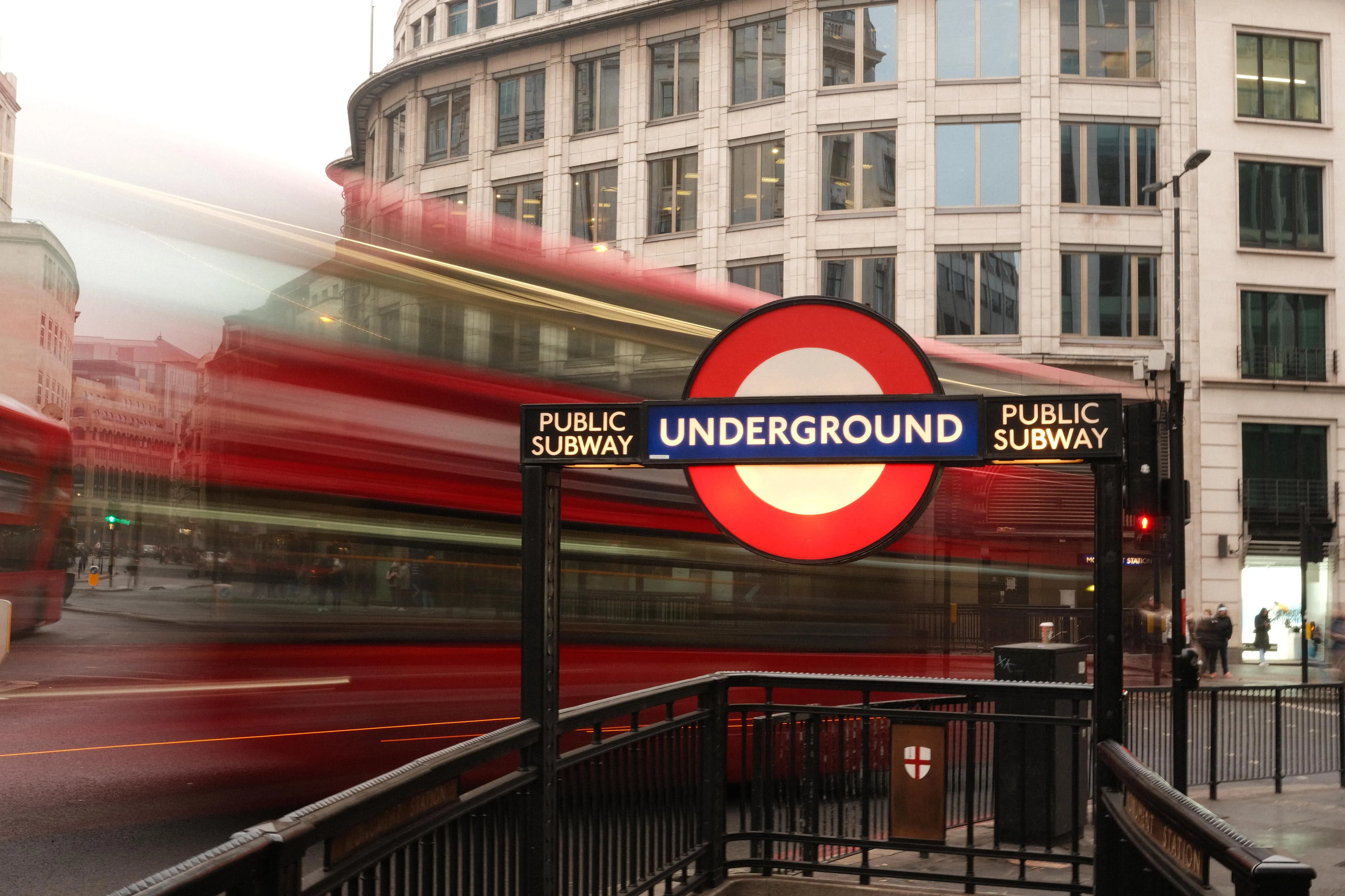 London Underground sign with a red bus blurred in motion